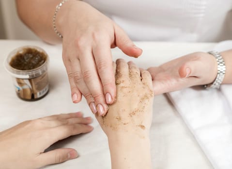 Manicure master does a peeling procedure on the hands of the client