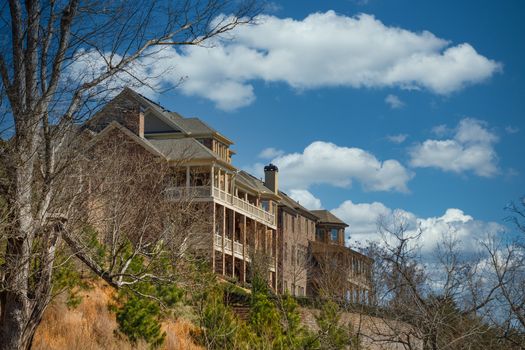 Two large brick homes with verandas on a hilltop under clear blue skies