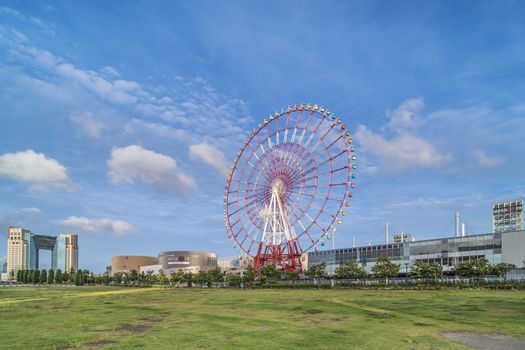 Odaiba colorful tall Palette Town Ferris wheel named Daikanransha visible from the central urban area of Tokyo in the summer blue sky. Passengers can see the Tokyo Tower, the twin-deck Rainbow Bridge, and Haneda Airport, as well as central Tokyo during their ride.