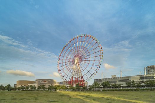 Odaiba colorful tall Palette Town Ferris wheel named Daikanransha visible from the central urban area of Tokyo in the summer blue sky. Passengers can see the Tokyo Tower, the twin-deck Rainbow Bridge, and Haneda Airport, as well as central Tokyo during their ride.