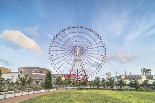 Odaiba colorful tall Palette Town Ferris wheel named Daikanransha visible from the central urban area of Tokyo in the summer blue sky. Passengers can see the Tokyo Tower, the twin-deck Rainbow Bridge, and Haneda Airport, as well as central Tokyo during their ride.