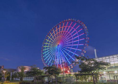 Odaiba illuminated Palette Town Ferris wheel named Daikanransha visible from the central urban area of Tokyo in the summer night sky. Passengers can see the Tokyo Tower, the twin-deck Rainbow Bridge, and Haneda Airport, as well as central Tokyo during their ride.