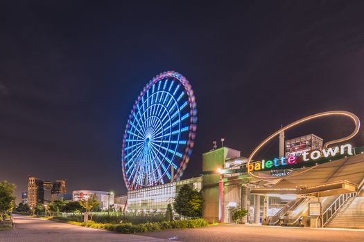 Odaiba illuminated Palette Town Ferris wheel named Daikanransha visible from the central urban area of Tokyo in the summer night sky. Passengers can see the Tokyo Tower, the twin-deck Rainbow Bridge, and Haneda Airport, as well as central Tokyo during their ride.