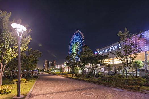 Odaiba illuminated Palette Town Ferris wheel close to the Venus Fort commercial area in the summer night sky. Passengers can see the Tokyo Tower, the twin-deck Rainbow Bridge, and Haneda Airport, as well as central Tokyo during their ride.