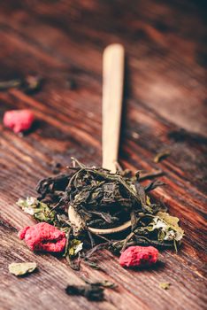 Wooden spoon of raspberry herbal tea over wooden table
