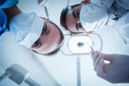 Low angle view of dentists in surgical masks holding dental tools