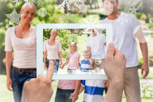 Hands holding tablet pc against adorable family during the summer 