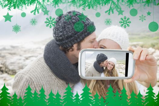 Hand holding smartphone showing man kissing a woman on rocky landscape