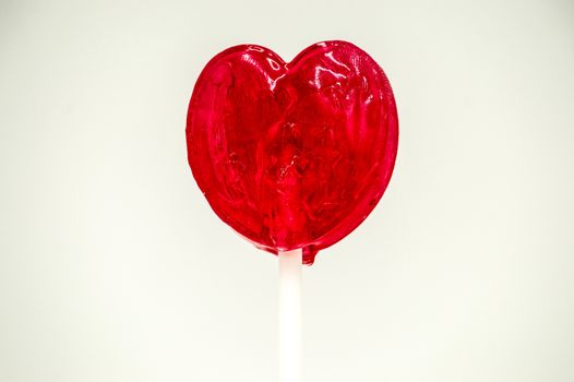 Heart shaped red lollipop on a white background