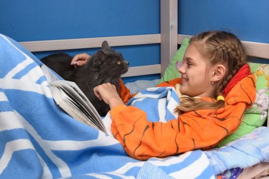 The girl rejoices in the cat who came to her bed