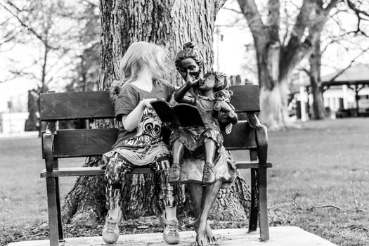 A little girl sitting on a bench in a park. High quality photo