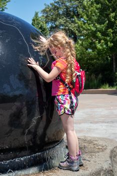 A little girl having a fun day at the zoo playing in a water fountain 