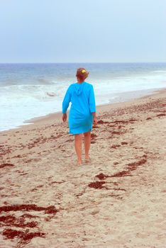 Mature female beauty walking in the sand on the beach outside.