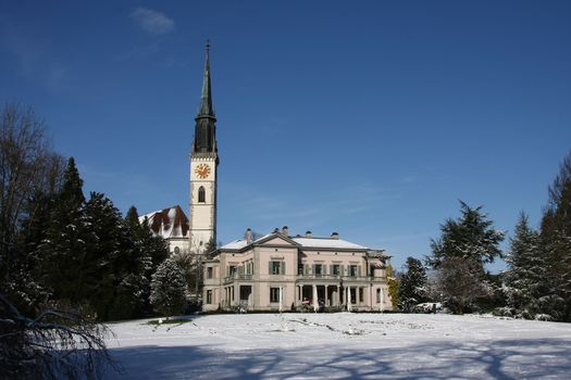 public park with church in Cham, Switzerland with tree and snow and a church