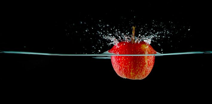 Apple splash in water with black background. Water shooting up into the air