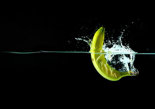 Banana splash in water with black background with copy space
