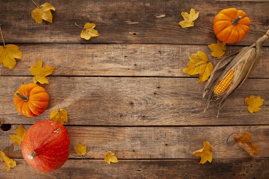 thanks giving setting with yellow leafs and pumpkins on a wooden background shot from above