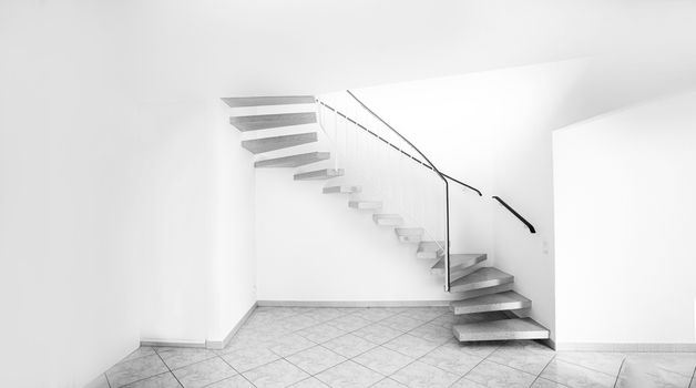 twisted staircase in clean white building leading up to second floor with white walls