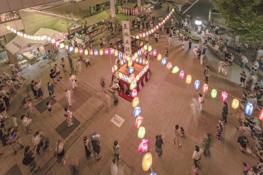 View of the square in front of the Nippori train station decorated for the Obon festival with illuminated paper lanterns  in the summer night with a yagura tower and paper lanterns in the Arakawa district of Tokyo.