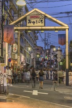 Japanese bear Shinto shrine mikoshi on their shoulders during the Obon festival in the retro old-fashionned shopping street Yanaka Ginza famous as a spectacular spot for sunset golden hour from the Yuyakedandan stairs which means Dusk Steps at Nishi-Nippori in Tokyo. Yanaka Ginza is also named the Evening Village.