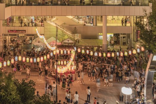 View of the square in front of the Nippori train station decorated for the Obon festival with illuminated paper lanterns  in the summer night with a yagura tower and paper lanterns in the Arakawa district of Tokyo.