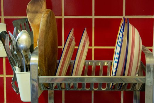 A dish rack with drying plates and cooking utensils