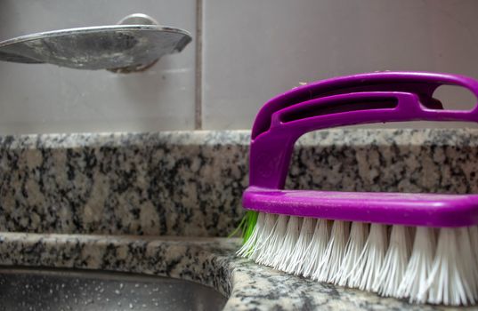 Purple cleaning brush on the top of a marble sink