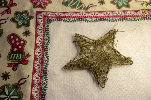 A golden star christmas decoration made of tangled wire on top of a thematic tablecloth