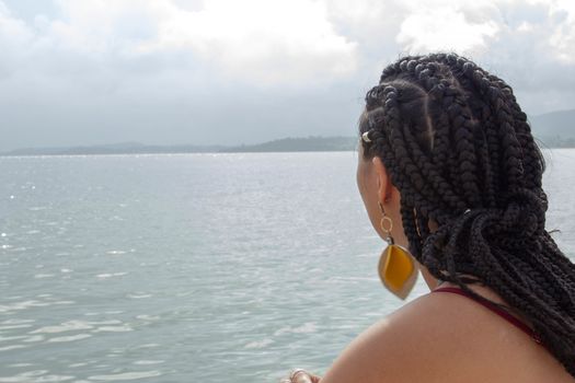 A beautiful woman with african braids hair gazing at the sea