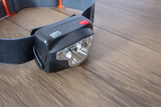 Black led headlamp turned off on a wooden table showing the elastic strap