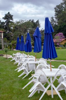 Plastic table and chairs with closed umbrellas on each one