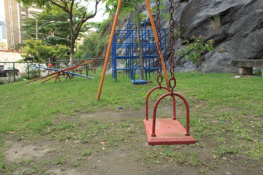 A kids playground on a park right next to a rock wall