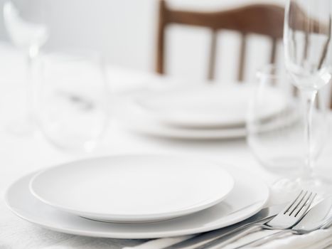 Beautiful table setting in white colors. Empty white plates. Set table for romantic dinner for two at home