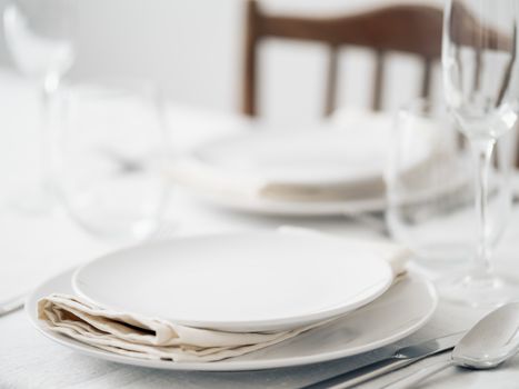 Beautiful table setting in white colors. Empty white plates. Set table for romantic dinner for two at home