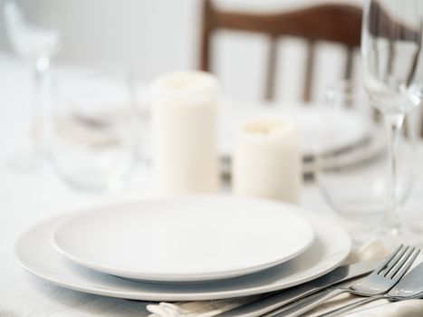 Beautiful table setting in white colors. Empty white plates. Set table for romantic dinner for two at home