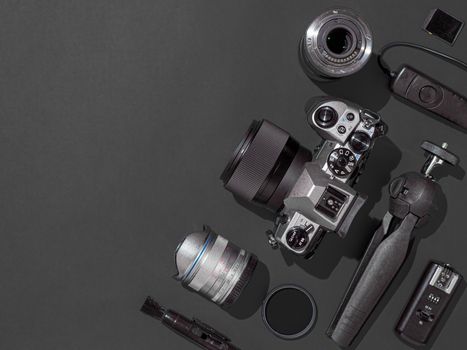 Photographer workplace with dslr camera, lens, pen tablet and camera accessories on black background. Camera, photography, visual content concept. Flat lay or top view. Copy space. Hard light.