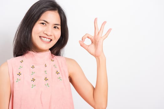 Portrait Asian beautiful young woman standing, She made finger OK symbol sign to agree and looking at camera, shoot photo in studio on white background, There was copy space