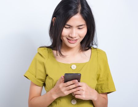 Portrait Asian beautiful happy young woman standing smile holding using mobile smart phone looking to smartphone, shoot the photo in a studio on a white background