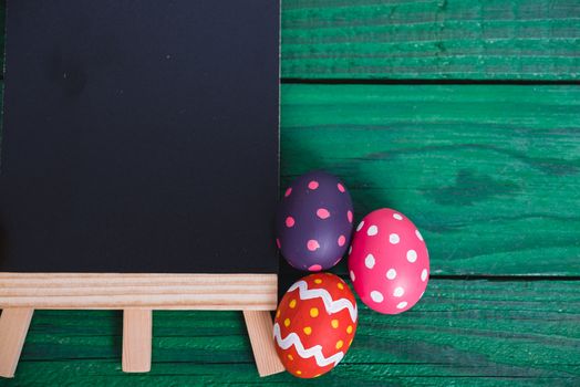 Easter eggs top view on green wooden background and have board work space board for use