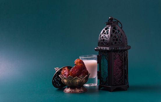 Ramadan Kareem fasting Food Concept, Bronze plate dates, milk, and lantern Aladdin lamp decoration, eid Arabian Muslim religious festival on a dark green background with copy space for text