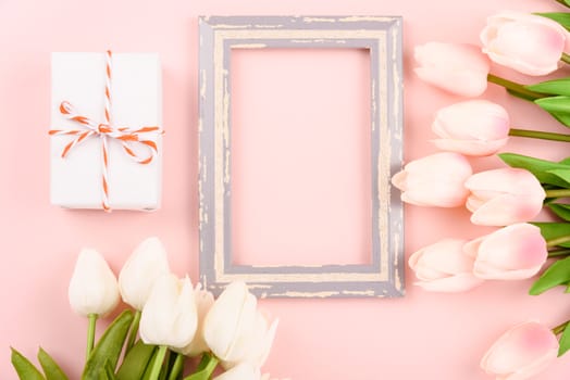 Happy Women's Day, Mother's Day concept. top view flat lay photo frame, gift box and Tulip flower on pink background, copy space for your text