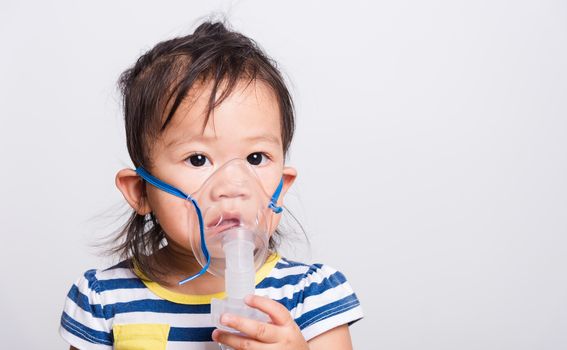 Closeup Asian face, Little baby girl sick her using steam inhaler nebulizer mask inhalation oneself on white background with copy space, health medical care