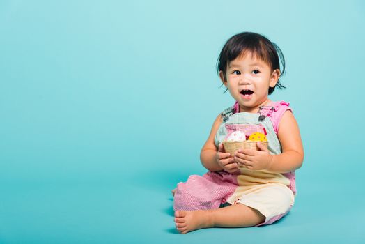 Asian Cute little baby girl beautiful holding Easter egg in basket, studio shot on blue background with copy space, Easter day concept