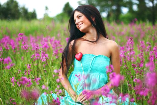 woman on summer flower field meadow heart in hands love nature