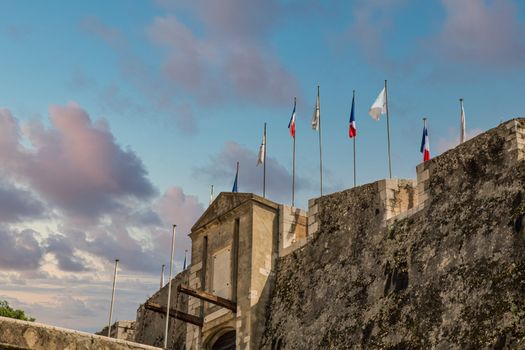 Flags in calm wind over a stone fortress under clear blue skies