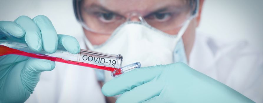 Coronavirus covid 19 infected blood sample in sample tube in hand of scientist with biohazard protection clothing in corona virus covid 19 research laboratory, coronavirus covid 19 vaccine research concept