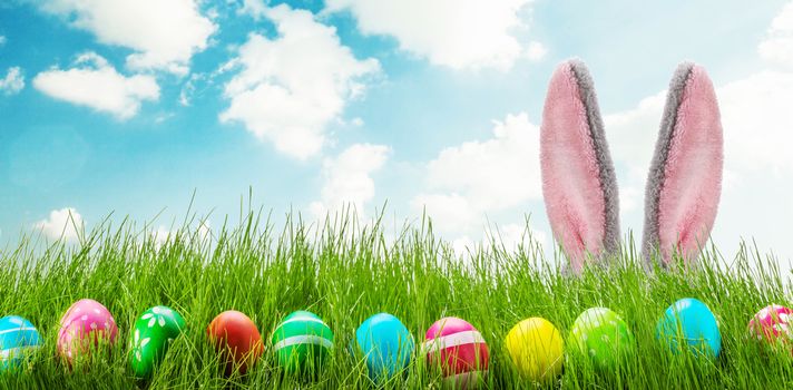 Easter bunny and Easter eggs on green grass meadow