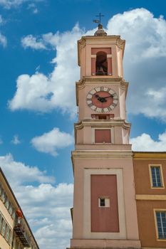A pink plaster clock tower under blue skies in Nice, France