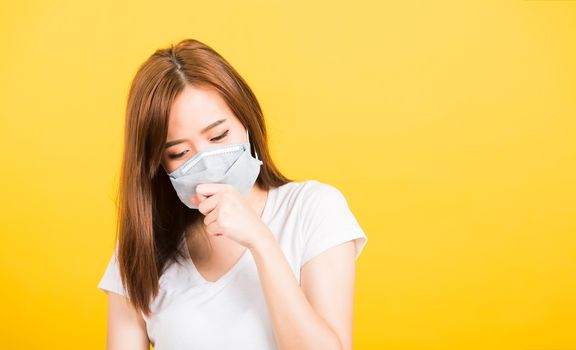 Asian happy portrait beautiful cute young woman teen standing wear t-shirt cough in mask protection from virus epidemic or air pollution isolated, studio shot on yellow background with copy space