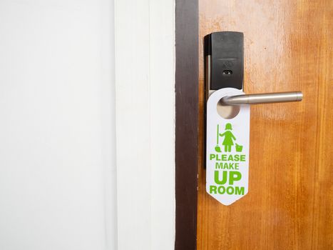 Make up room sign attached to the front of the room that is closed inside the hotel on the wooden door with stainless steel handles and use the electronic key system.